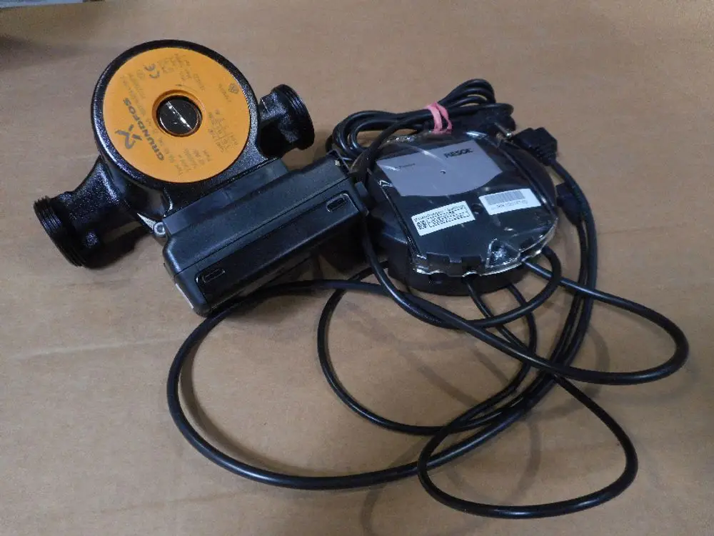 Remeha Solarpumpe mit orangefarbener Kennzeichnung und mehreren Kabeln. Die Pumpe hat eine Verbindungseinheit und ist für die Installation in einem Solarsystem vorgesehen.